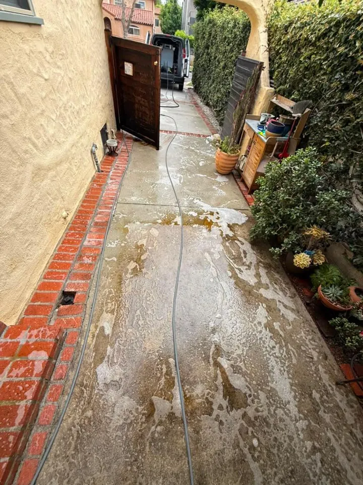 Brown dirty runoff lifting off a concrete walkway during cleaning