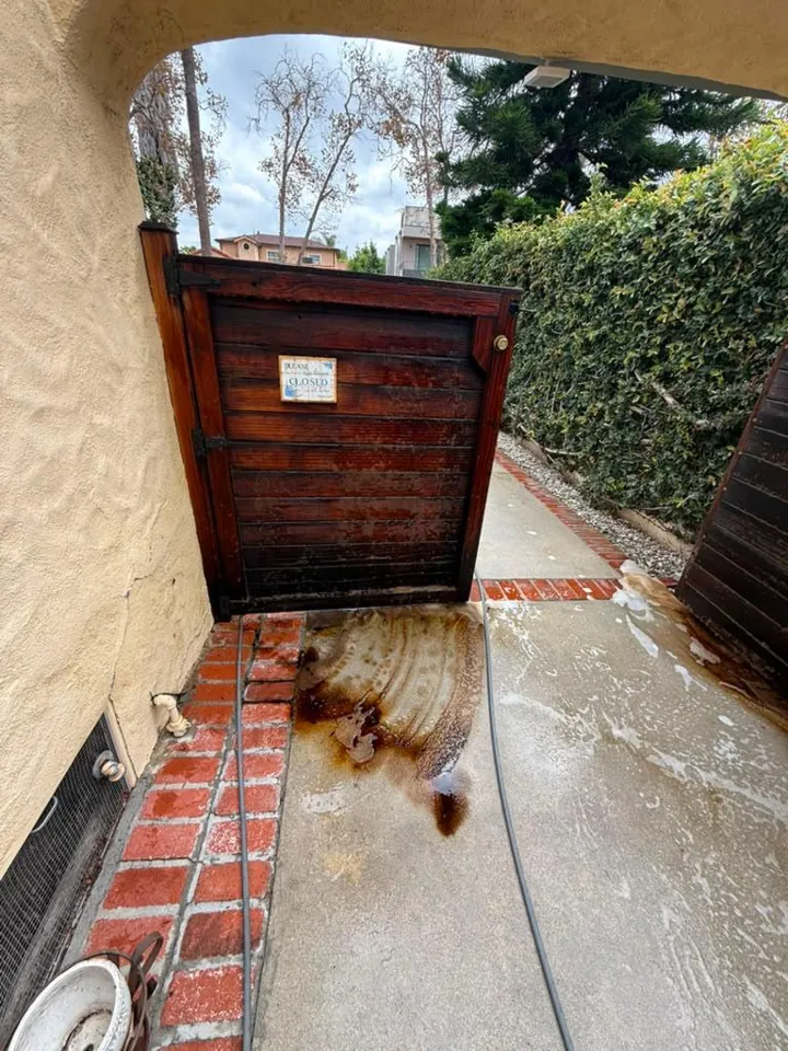 Brown stain running from a dark wood gate onto the concrete below it